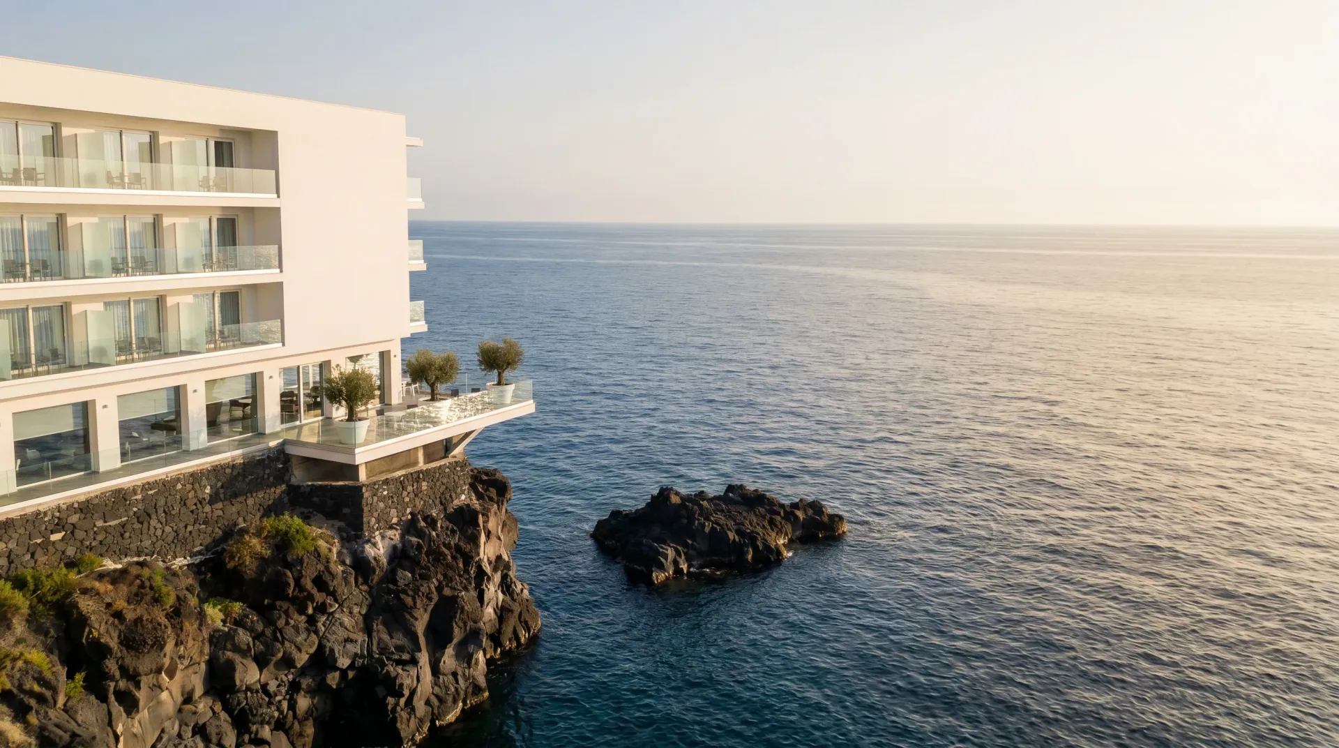 L’Hotel Nettuno, hotel bianco affacciato sulla scogliera lavica e sul Mar Ionio a Catania al tramonto